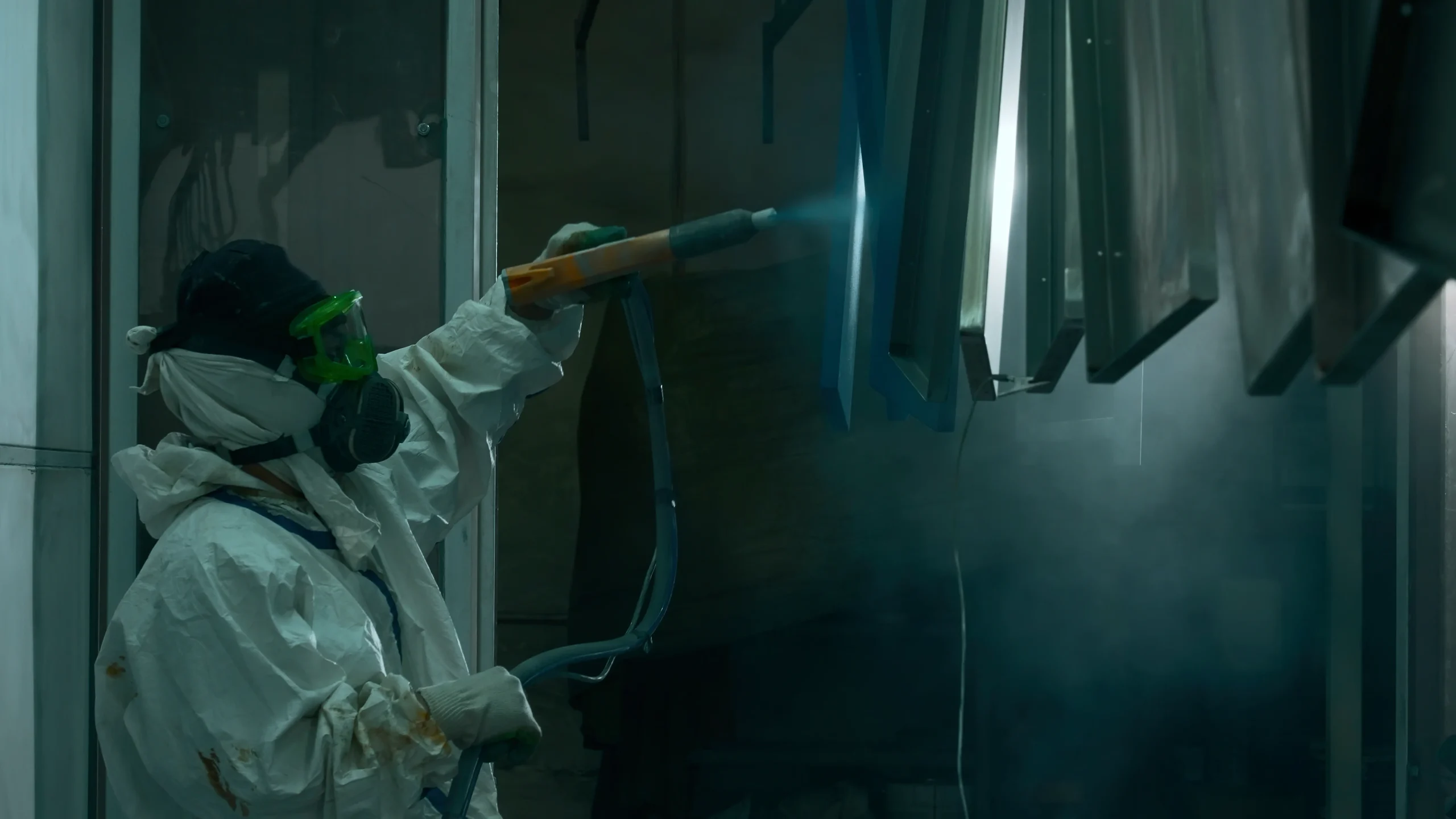 Worker applying powder coating to a metal part with a spray gun